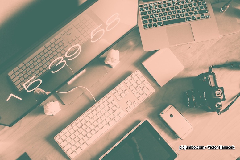 Computerbildschirm, Tastatur, Maus, Laptop und Kamera auf einem Schreibtisch