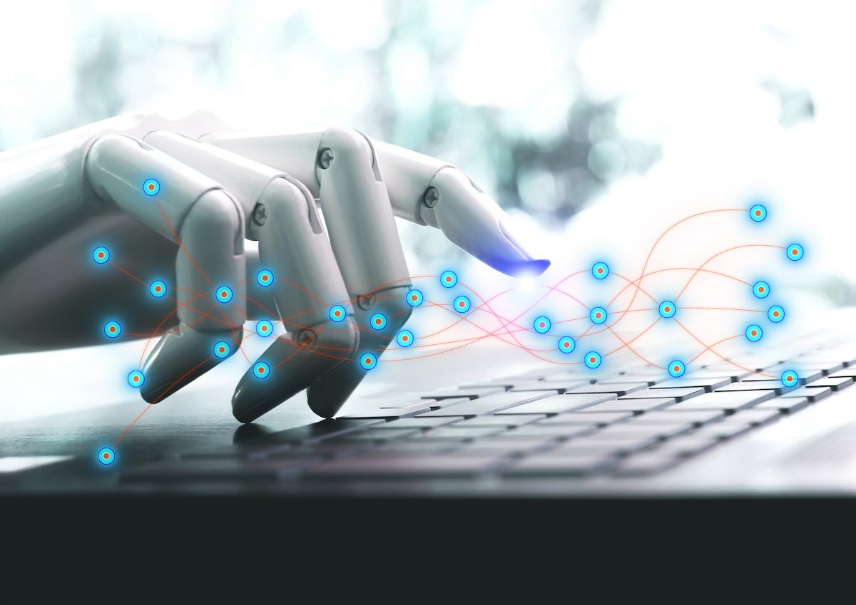 Chat GPT künstliche Intelligenz. Eine Roboterhand streckt einen Zeigefinger aus, um auf eine Tastatur zu klicken.